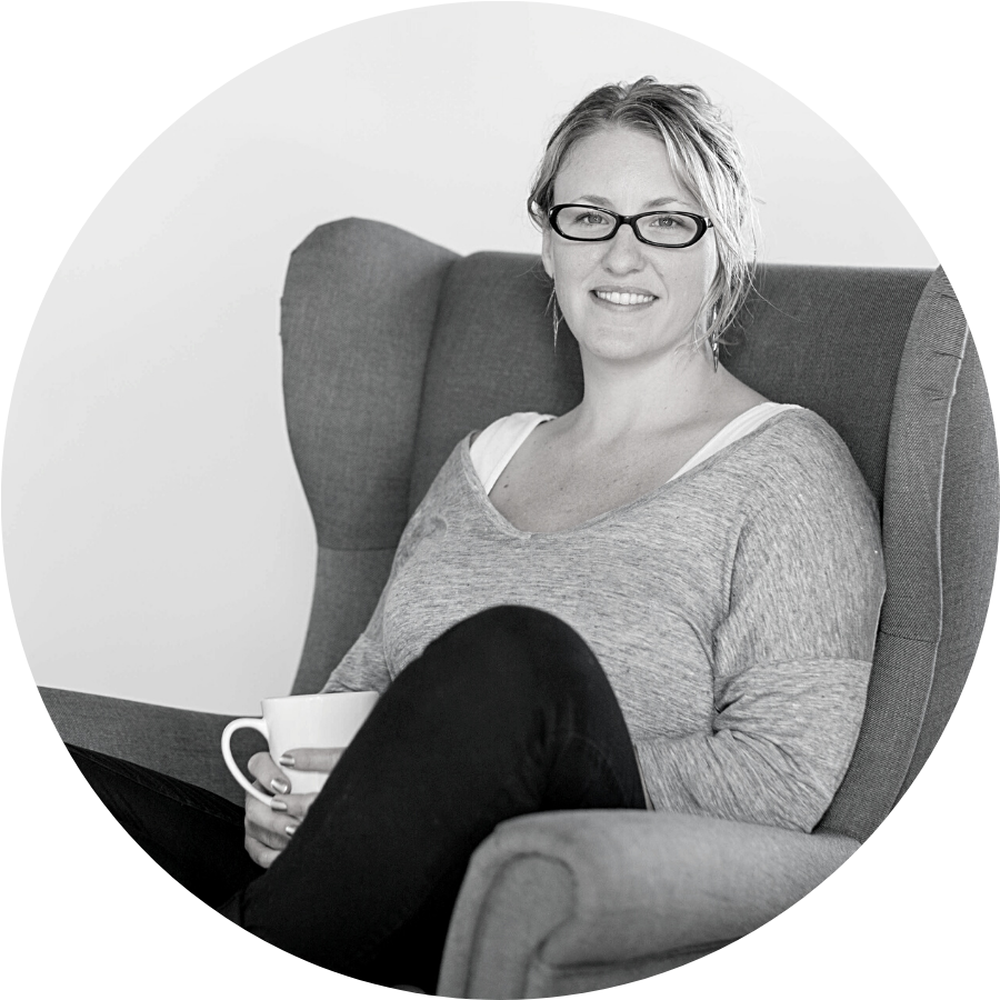 Parrish Wilson, a white woman, is sitting cross-legged in an armchair with a mug of tea.