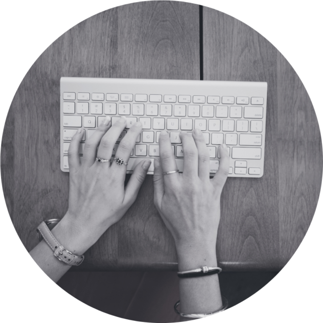 Two hands type on a white keyboard. The image is in black and white.